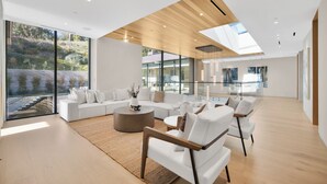 A spacious living room with a large sofa set, a coffee table, and a wooden ceiling. - Hutton Villa - Luxury Modern Retreat in Iconic Beverly Hills Oasis (Beverly Hills)