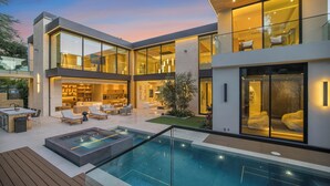 A modern two-story house with a swimming pool, outdoor seating, and a well-lit interior. - Hutton Villa - Luxury Modern Retreat in Iconic Beverly Hills Oasis (Beverly Hills)