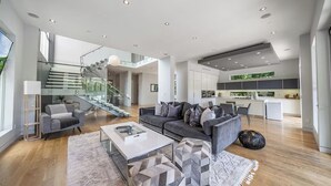 Ett rymligt vardagsrum med en modern soffa, ett soffbord och en trappa som leder upp till en övre våning.
