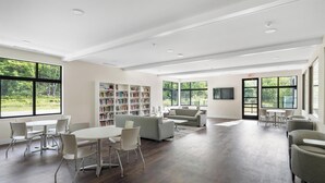 A spacious library with a large window, a sofa, and a table with chairs. - Peaceful 3-Bedroom Retreat with Lake Michigan Views & Access (Harbor Springs)