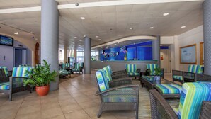 A lobby with wicker furniture, potted plants, and a reception desk.