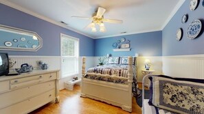 A bedroom with a bed, dresser, and a ceiling fan.