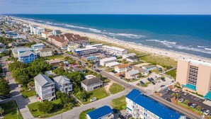 Vue aérienne d’une ville côtière avec une plage, des bâtiments et une route menant à la plage.