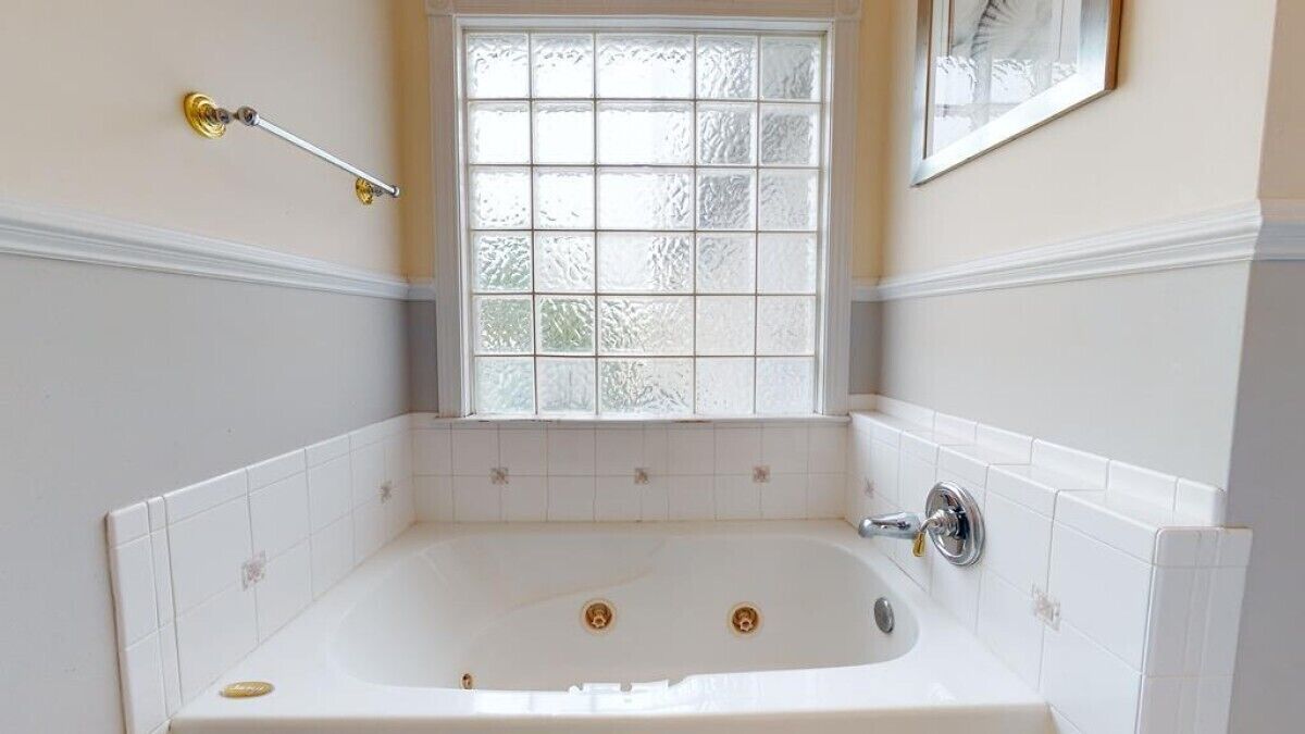 A bathroom with a freestanding bathtub, a window with frosted glass, and a towel rack.