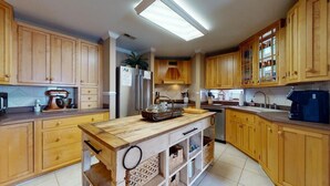 Une cuisine avec des meubles en bois, un îlot central et un réfrigérateur.