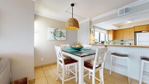 Una cocina moderna con armarios blancos, una mesa de comedor con sillas y una lámpara colgante.