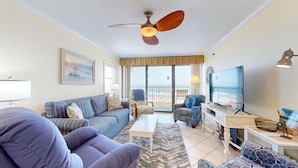 A living room with a sofa, armchairs, a coffee table, a TV, and a ceiling fan. - Pelican Watch 301-Beautiful Third Level Oceanfront 3 Bedroom 2 bath End Unit with elevator (Carolina Beach)