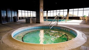 An indoor swimming pool with a 3 FT depth, surrounded by a tiled deck and a poolside area with chairs and a trash bin. - Pelican Watch 301-Beautiful Third Level Oceanfront 3 Bedroom 2 bath End Unit with elevator (Carolina Beach)