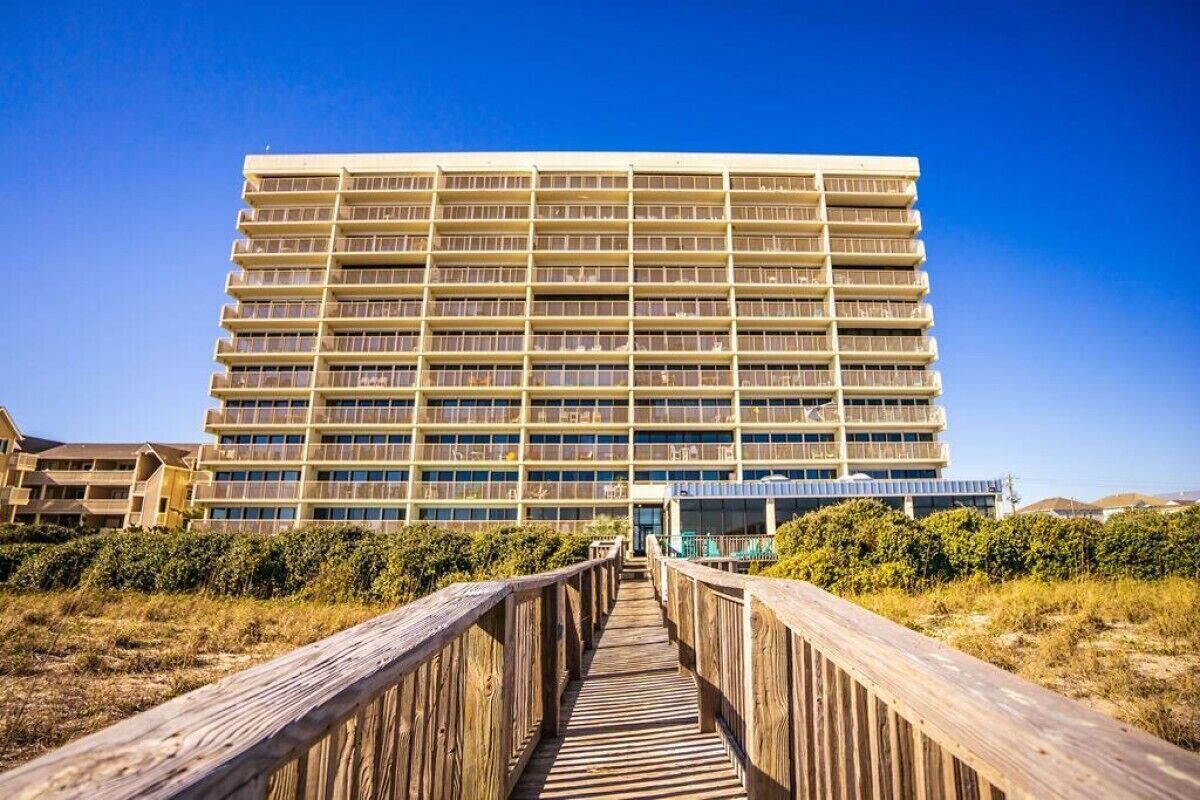 A multi-story hotel with a wooden walkway leading to the entrance.