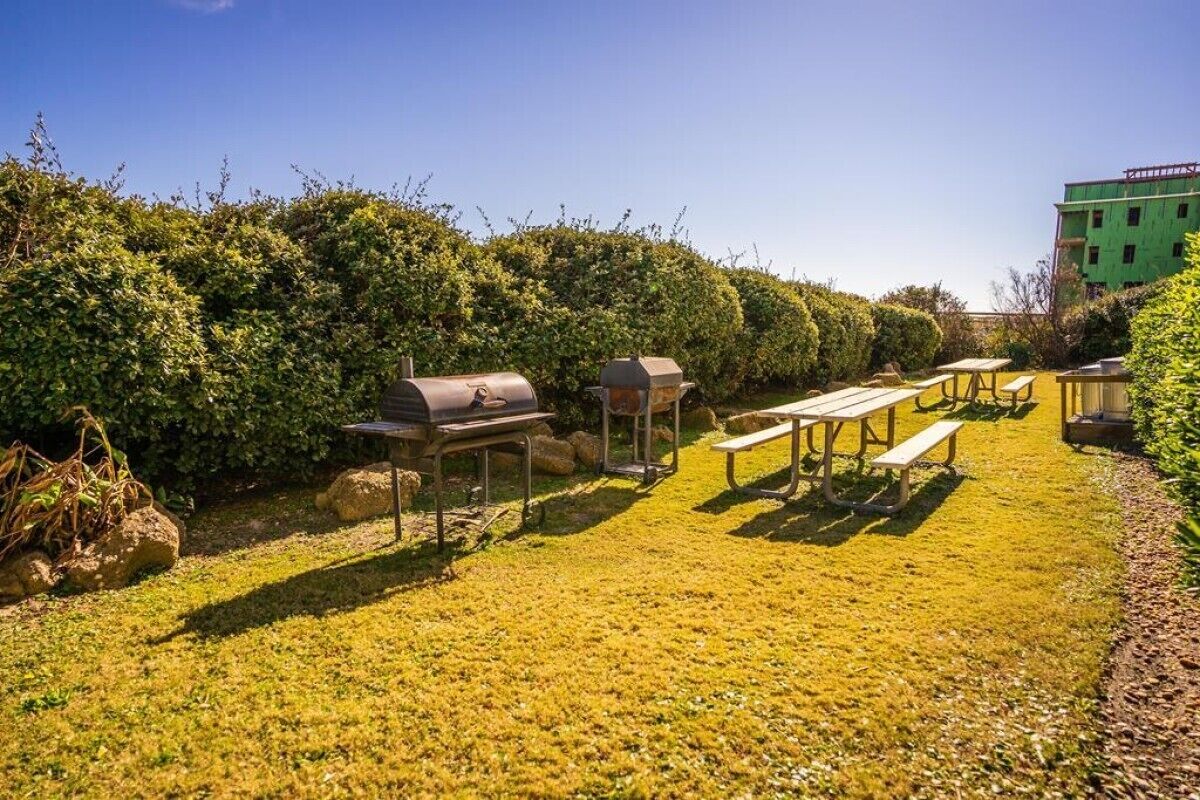 En baghave med grillområde, picnicborde og en bygning i opførelse.