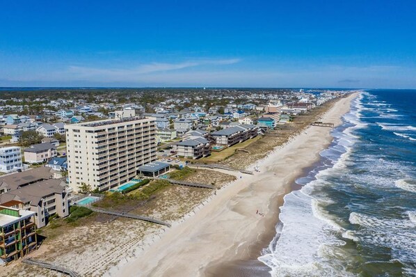 Une ville côtière dotée d’une longue plage de sable, d’un grand hôtel à plusieurs étages et offrant une vue dégagée sur l’océan.