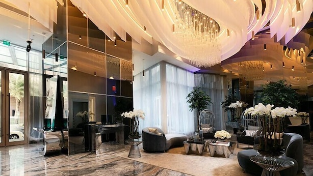 A spacious lobby with a marble floor, modern seating, a large chandelier, and large windows allowing natural light. - High End Luxury Stay with Full Palm Jumeirah View (Dubai)