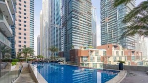 A modern residential building with a rooftop swimming pool, surrounded by high-rise buildings. - High End Luxury Stay with Full Palm Jumeirah View (Dubai)