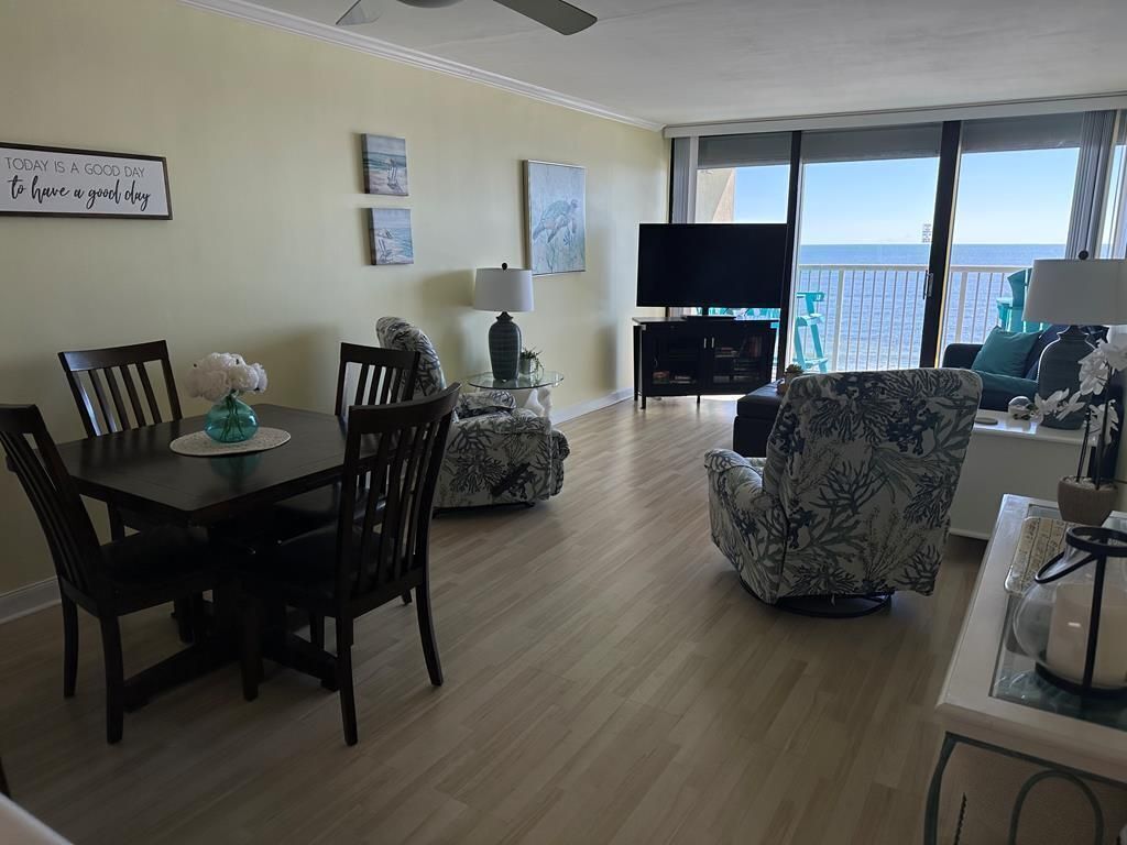 Una sala de estar con comedor, televisor y balcón con vista al océano.