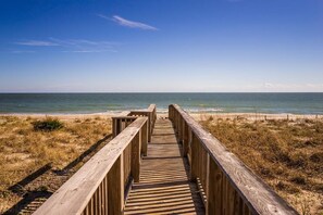 Une promenade en bois qui mène à une plage offrant une vue dégagée sur l’océan.