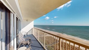 A balcony with a view of the ocean, a table with chairs, and a railing. - Pelican Watch 907-Lovely end unit with views galore and elevators (Carolina Beach)