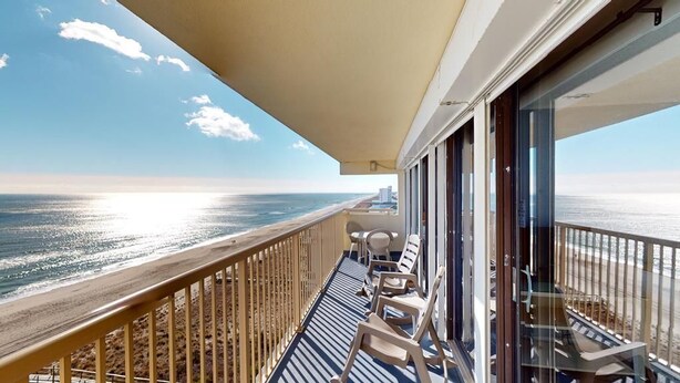 A balcony with a view of the ocean, a railing, and a few lounge chairs. - Pelican Watch 907-Lovely end unit with views galore and elevators (Carolina Beach)