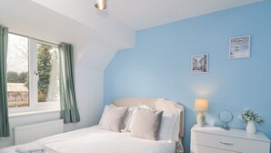 A bedroom with a bed, a dresser, a window with curtains, and a wall with two pictures. - 20 Honeycroft (Cheltenham)