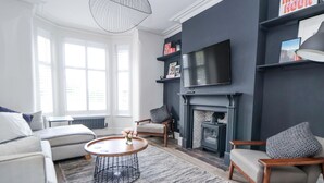 A modern living room with a fireplace, a sofa, a coffee table, and a television.