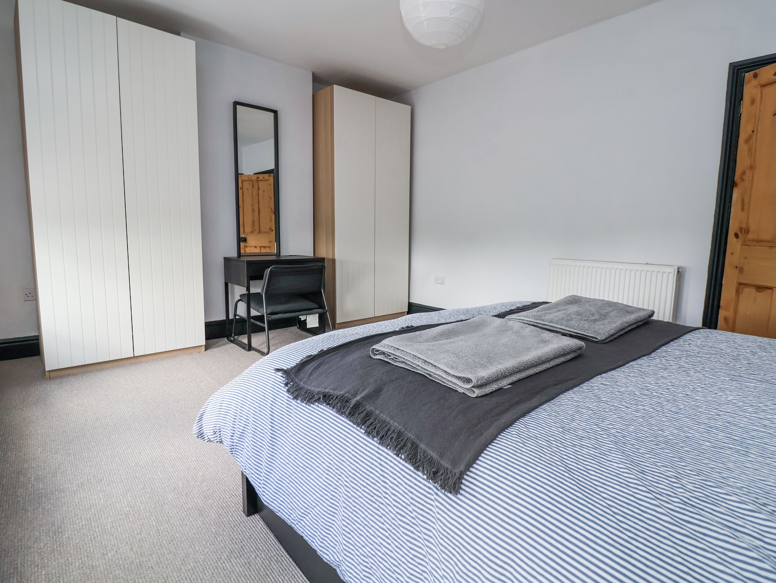 A bedroom with a bed, a desk, and a wardrobe.