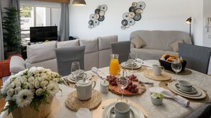 Un comedor con una mesa dispuesta para el desayuno, que incluye platos, vasos y una bandeja de fruta.