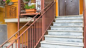 Un escalier en marbre, agrémenté d’une rampe métallique, mène à une porte.
