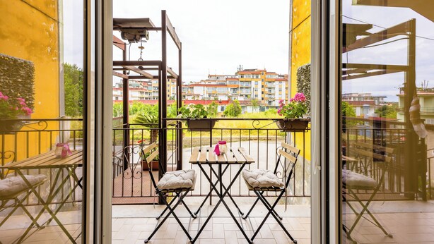 Un balcon avec une table et des chaises, une balustrade et des plantes en pot.