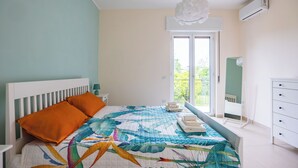 Une chambre à coucher comprenant un lit, une table de chevet, une commode, une fenêtre et un appareil de climatisation.