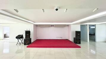 Una stanza ampia con tappeto rosso, pareti bianche e condizionatori a soffitto.