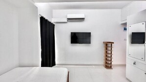 Una habitación de hotel moderna con cama, televisión, aire acondicionado y armario.