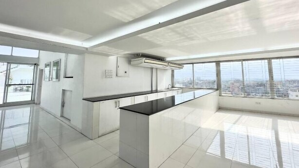 Una cocina moderna con una isla central, ventanas amplias y vistas a la ciudad.