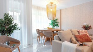 A modern living room with a sofa, a dining table with chairs, a hanging light fixture, and a potted plant. - Genteel Home Fuente Nueva (Granada)