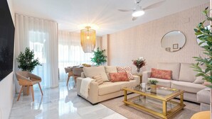 A modern living room with a sofa, coffee table, and a dining area. - Genteel Home Fuente Nueva (Granada)