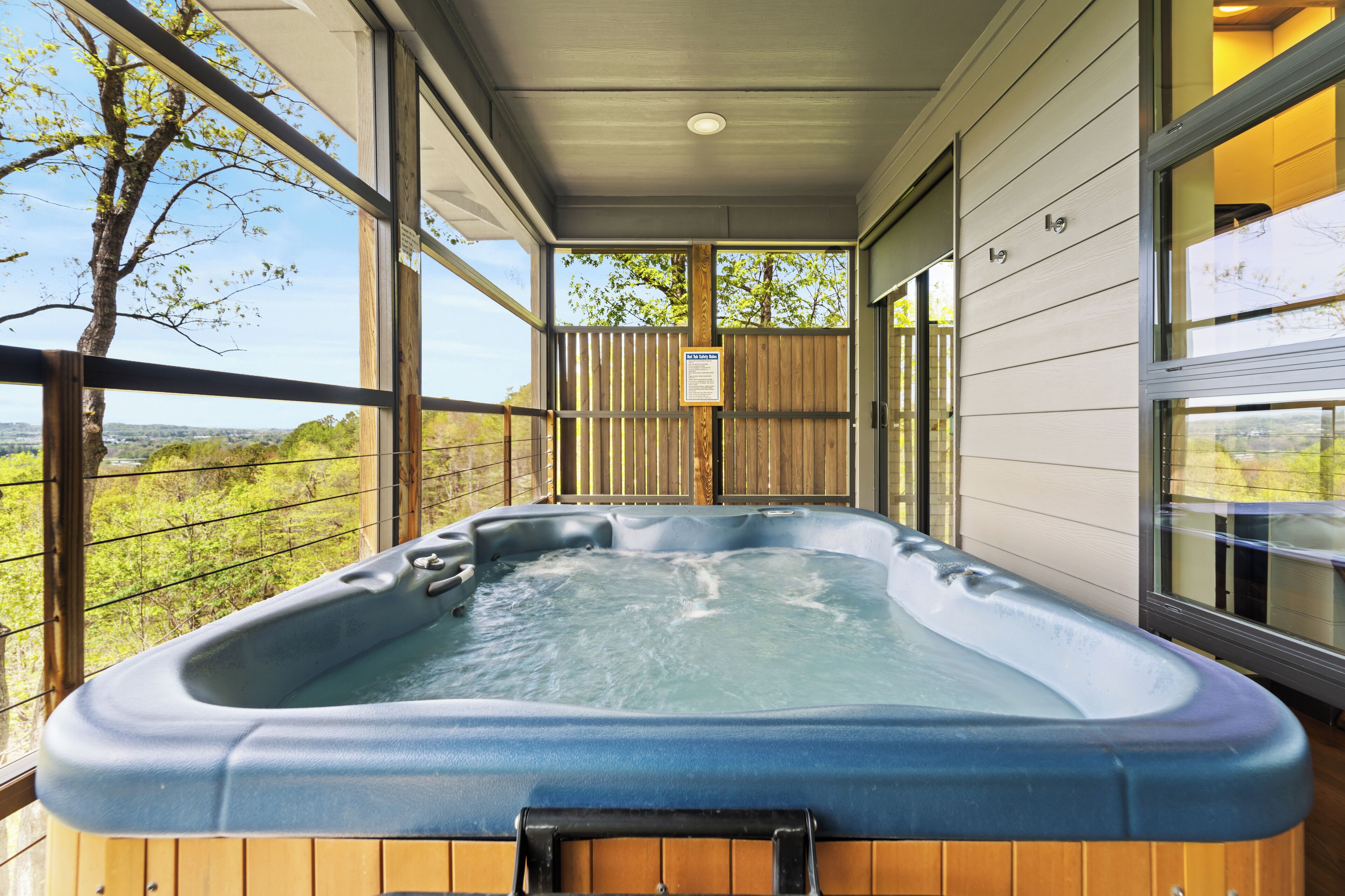 Een hottub op een balkon met uitzicht op bomen en een verre landschappen.