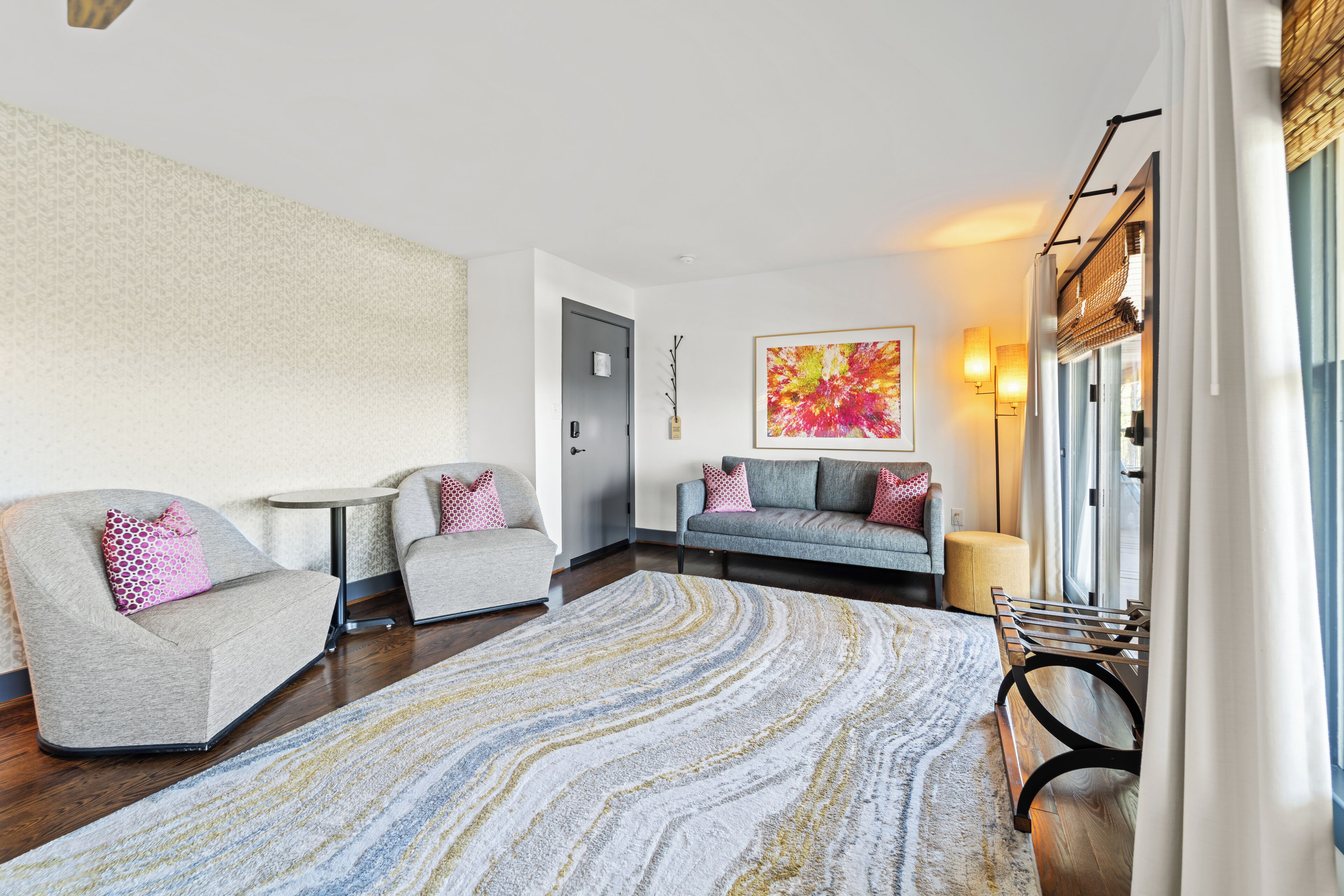 Una sala de estar moderna con un sofá, sillones, una mesa de centro y una alfombra estampada.