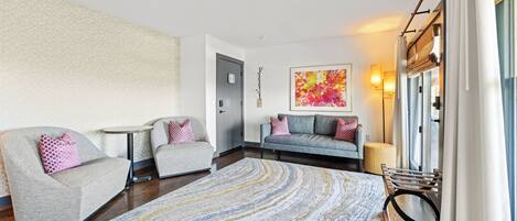 Una sala de estar moderna con un sofá, sillones, una mesa de centro y una alfombra estampada.
