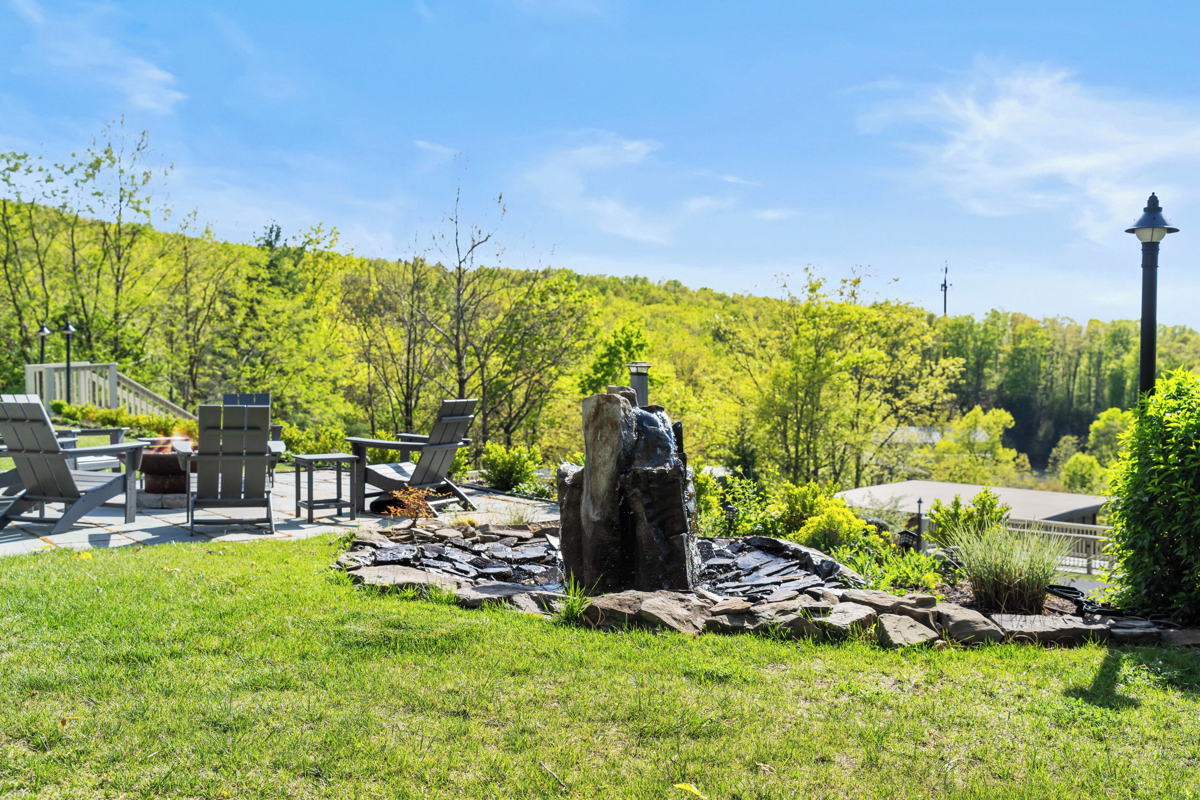 A patio area with outdoor furniture, a stone sculpture, and a view of a forested hill.