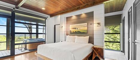 A spacious bedroom with a large bed, wooden ceiling, and a view of the outdoors.
