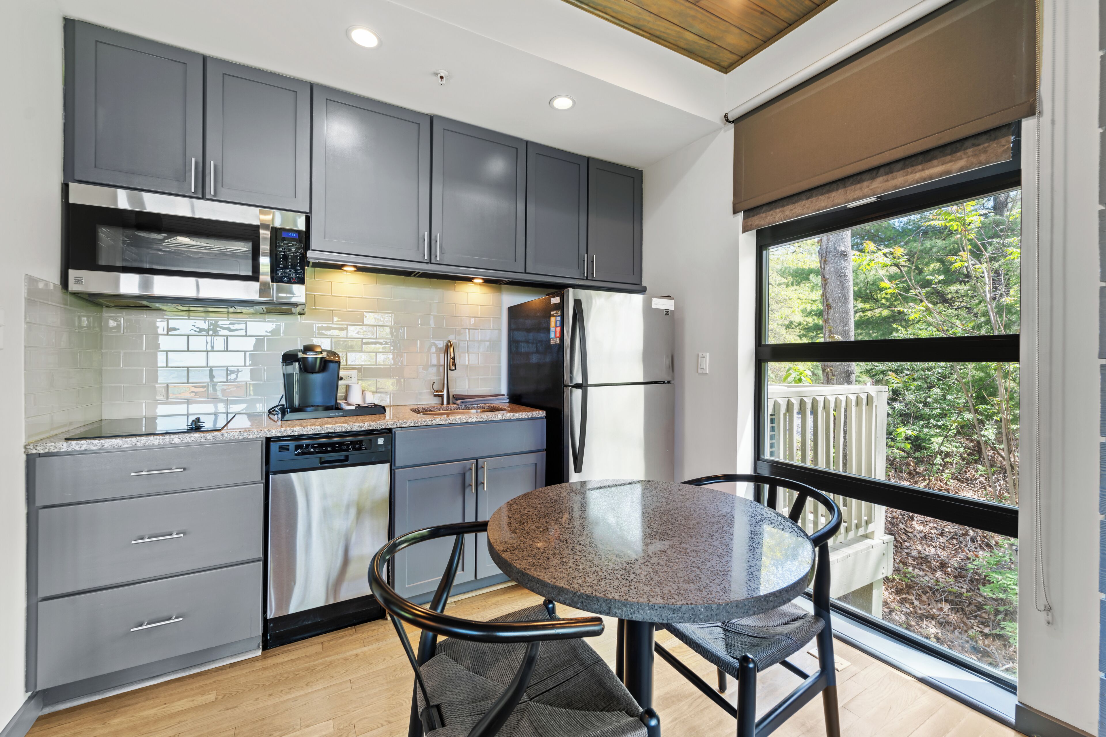 A modern kitchen with grey cabinets, stainless steel appliances, and a round table with chairs.