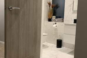 Een badkamer met toilet, wastafel en spiegel.