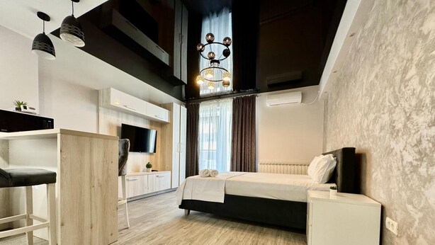 A modern bedroom with a bed, bedside table, and a desk area with a chair.