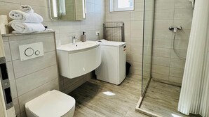 A modern bathroom with a toilet, sink, and shower.
