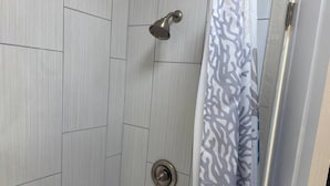 Un espace douche au design moderne, comprenant une pomme de douche et un robinet de réglage.