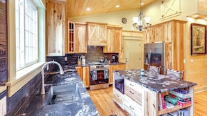 A kitchen with wooden cabinets, a central island with a sink, a stove, and a refrigerator.