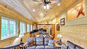 A cozy cabin interior with a dining area, sofa set, and a ceiling fan.