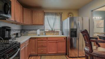 Kitchen area with an oven, microwave, and sink, featuring a window with sheer curtains.