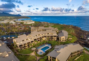 A resort with a swimming pool, multiple buildings, and a view of the ocean.