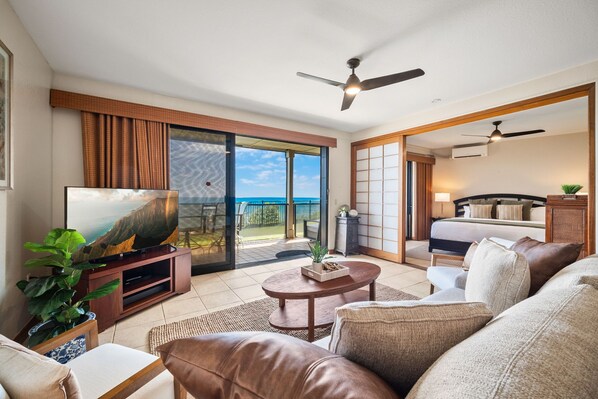 A living room with a television, sofa, coffee table, and a view of the outdoors.
