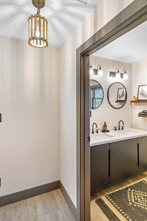 A modern bathroom with a double sink, vanity, and a ceiling light fixture.