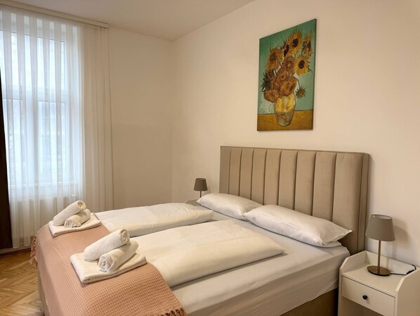 A hotel room with two beds, a painting on the wall, a nightstand, and a window with curtains. - Apartment in Staatsoper Nähe Prime Location (Vienna)